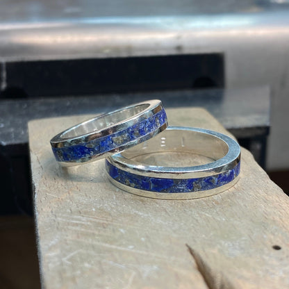 Two silver rings with blue inlay lapis lazuli on a stone surface
