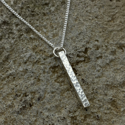 Silver necklace with a textured pendant on a stone surface