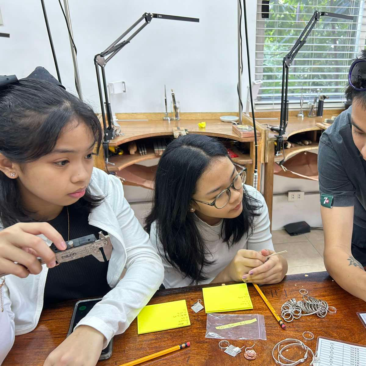 Three people working on a craft project at a table with various materials.