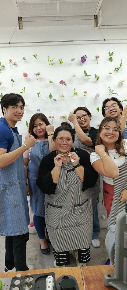 Employee engagement teambuilding jewelry making group of people posing together in front of a floral wall